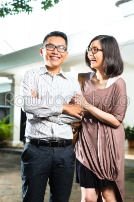 Asian homeowner couple in front of home