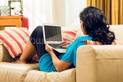 Asian Woman sitting on couch and surfing the internet