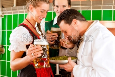 Couple with beer and their brewer in brewery