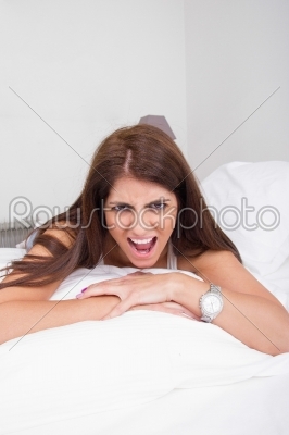 angry young woman lying on the bed shouting