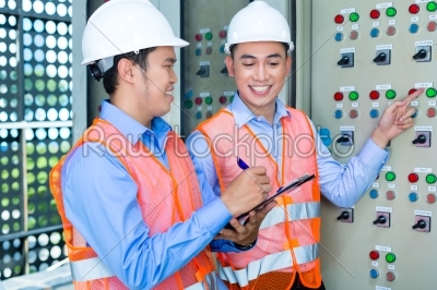 Asian technicians at panel on construction site