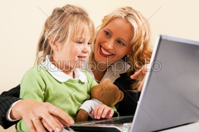 Businesswoman and mother showing kid the internet
