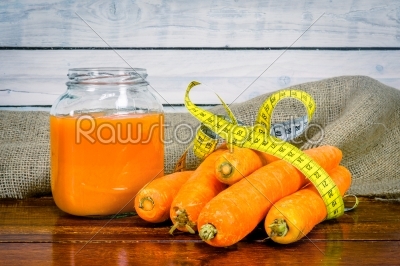 Carrots with measure tape and juice on a table