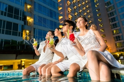 Chinese couples drinking cocktails in hotel pool bar
