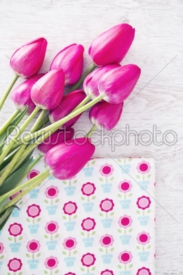 Collection of spools  threads in pink colors arranged on a white wooden background with tulips