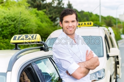 Driver in front of taxi waiting for clients