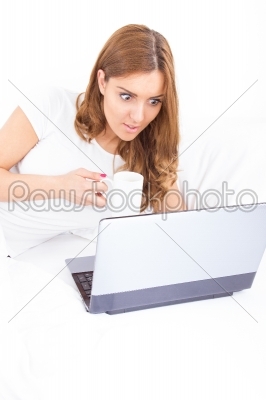 portrait of confused and surprised woman using laptop drinking c