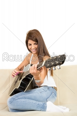 pretty girl playing guitar on the sofa
