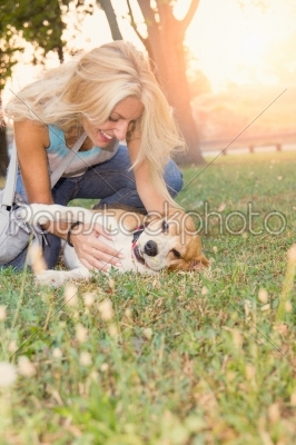 pretty smiling blonde woman playing with dog on the grass