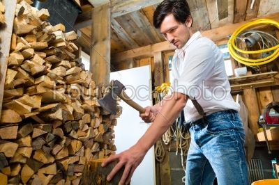 Young man chopping fire wood in mountain chalet