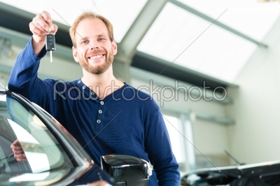 Young man with auto in car dealership